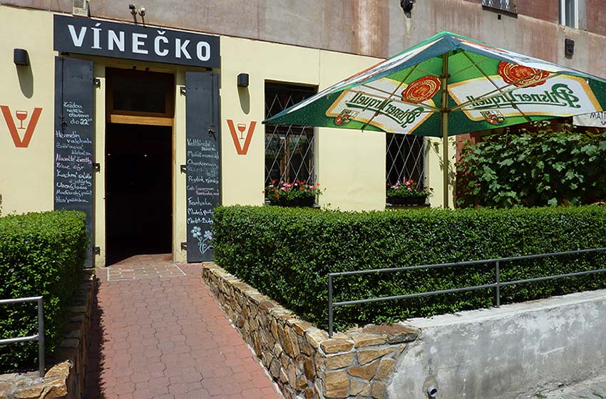 Vstup do vinárny Vínečko z ulice Londýnská s cedulí a znakem V